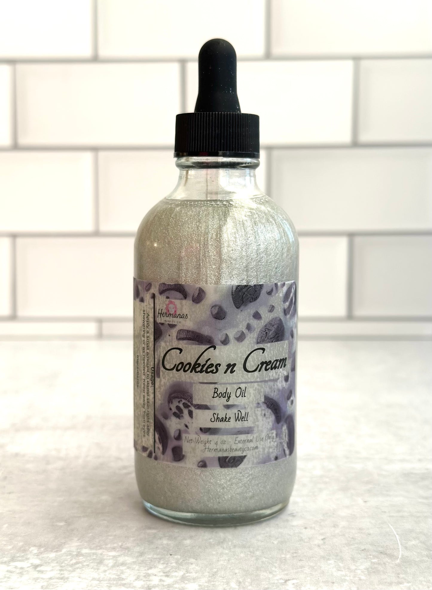 Body Oil in glass bottle with black dropper top. The label is black and gray and has cookies on it
