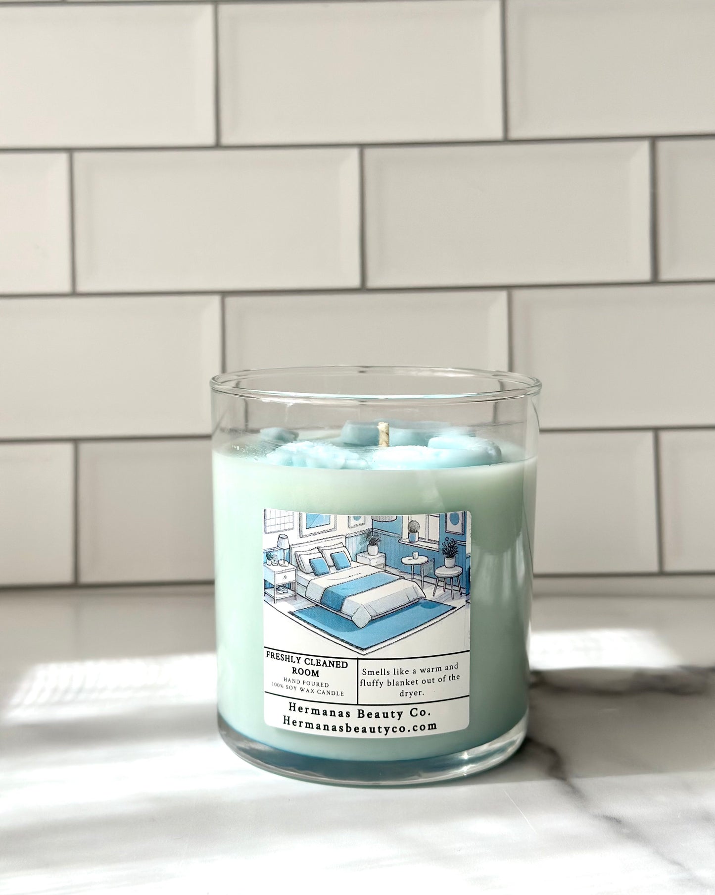 Light blue candle in clear glass jar, has a white and blue label