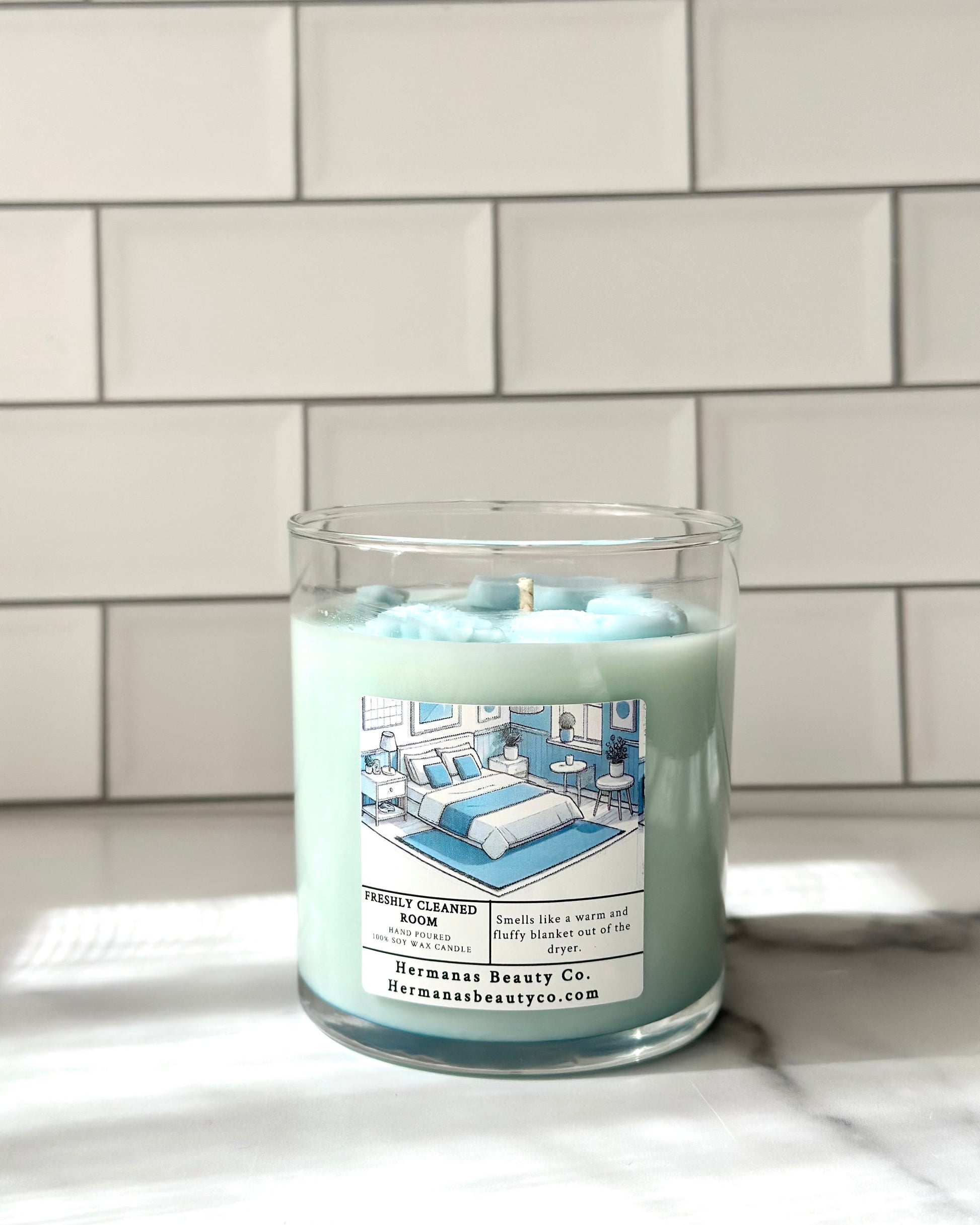 Light blue candle in clear glass jar, has a white and blue label