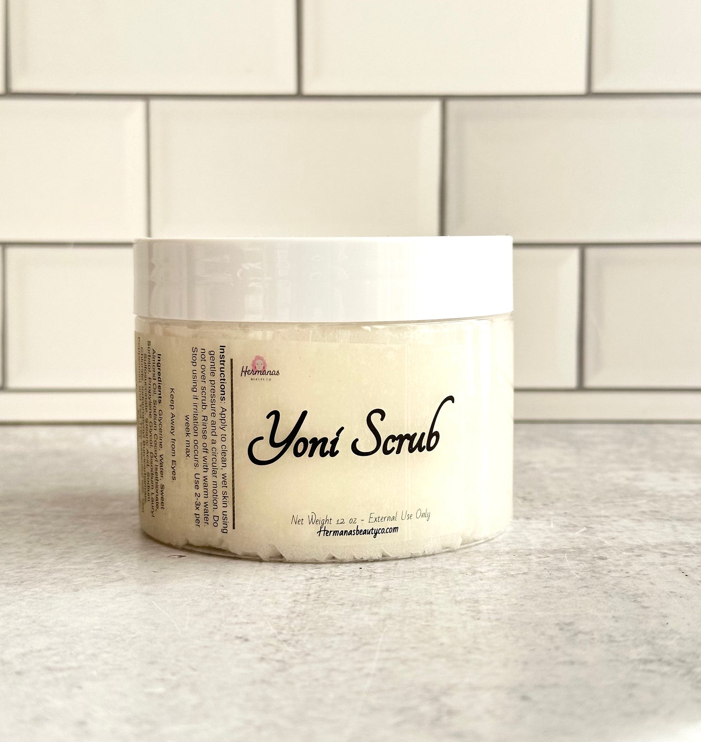 Jar of Yoni scrub, the jar is clear with a white lid, and a label that reads Yoni Scrub