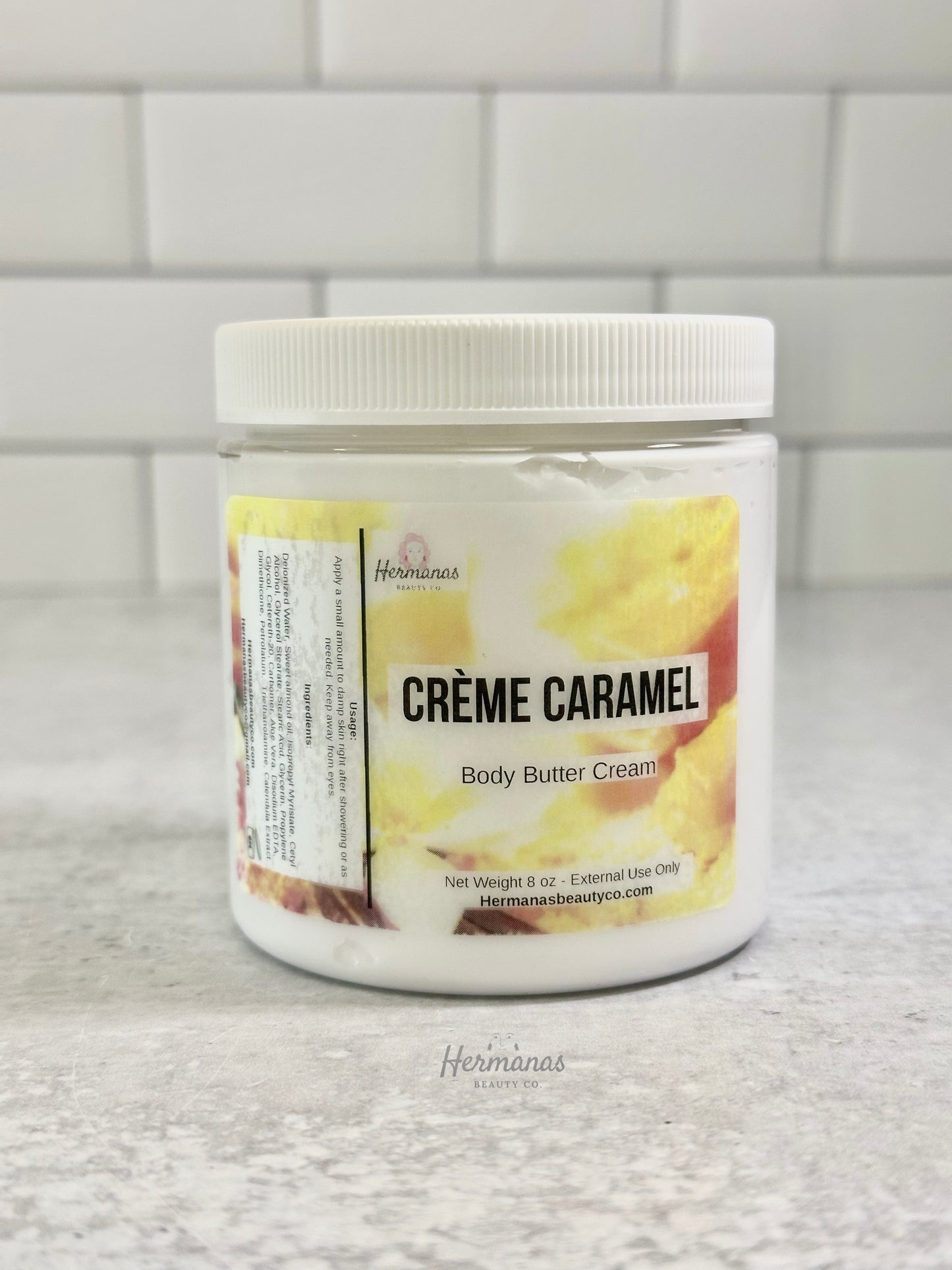 Jar of Crème Caramel body butter cream on a tiled wall background