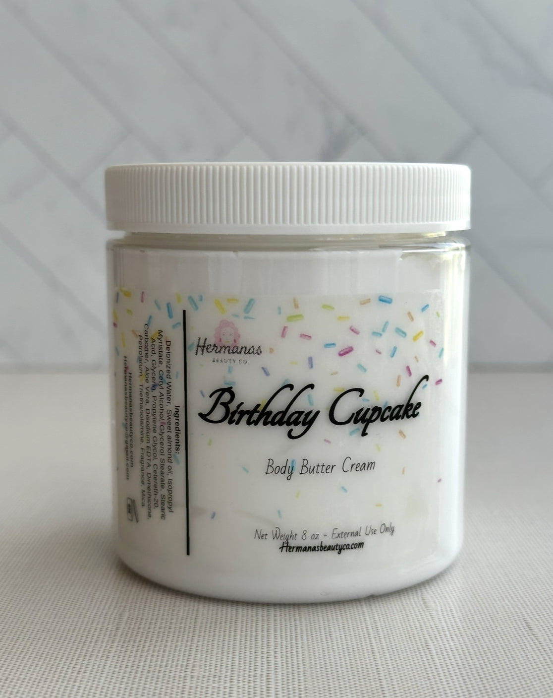 Jar of 'Birthday Cupcake' body butter cream with colorful sprinkles on a white background