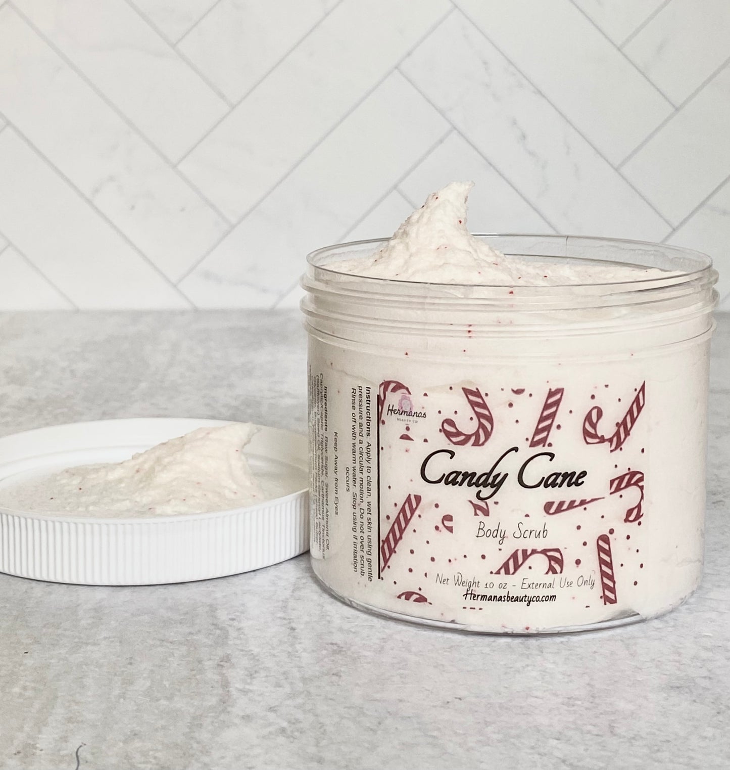 Body scrub jar filled with body scrub and festive red label featuring candy canes. White top