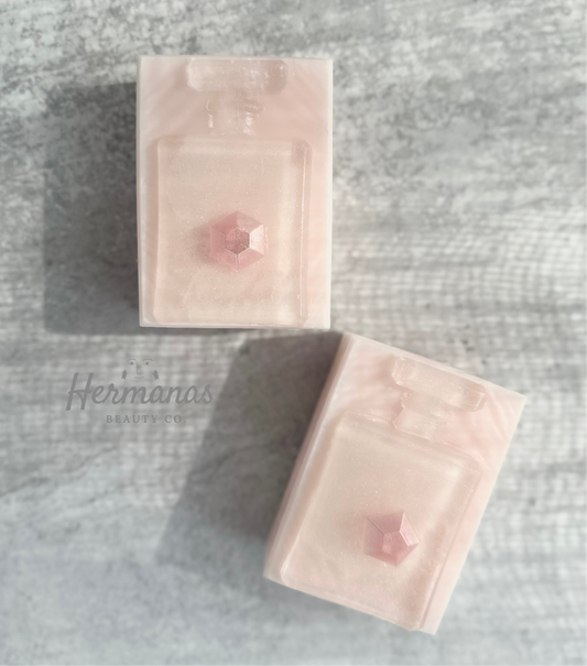 Rectangular shaped light pink soap with a clear perfume shaped soap on top. 