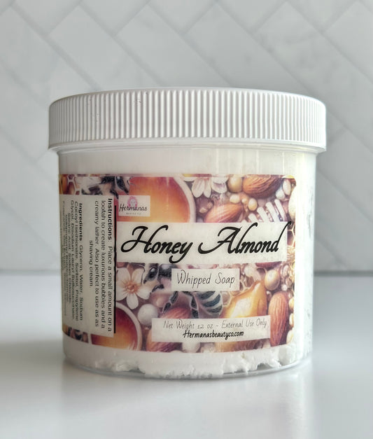 Clear whipped soap jar with a brown label with flowers, bees, honey and almonds on it.