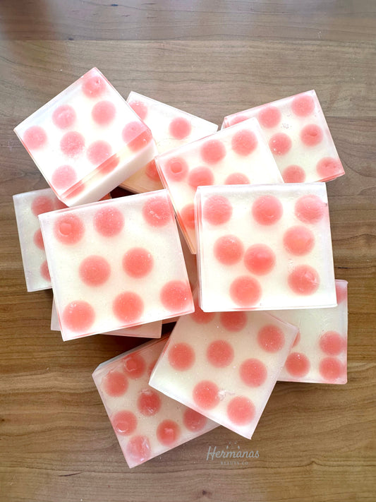 Square soap bar with a white background and pink round soap pieces