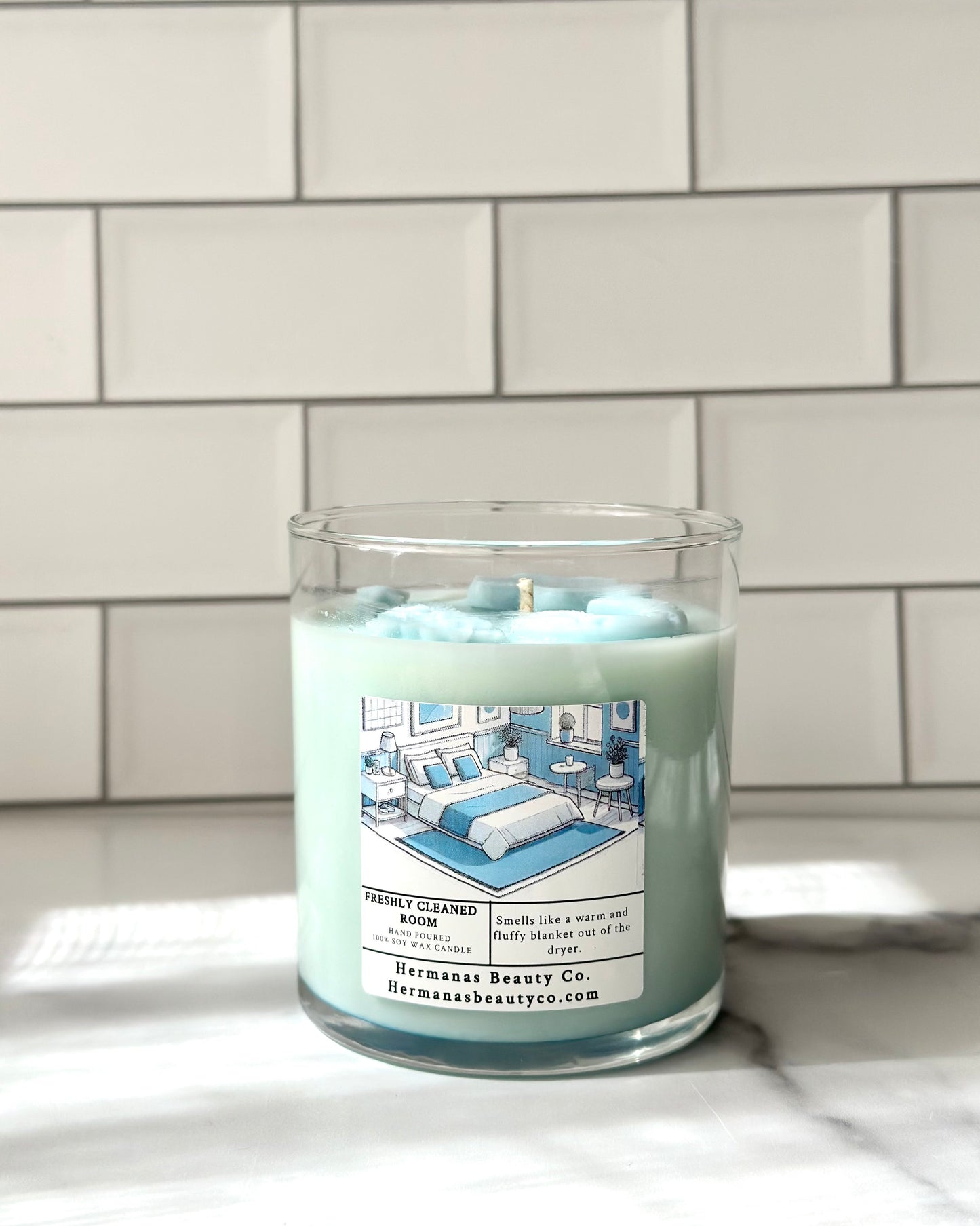 Light blue candle in clear glass jar, has a white and blue label 