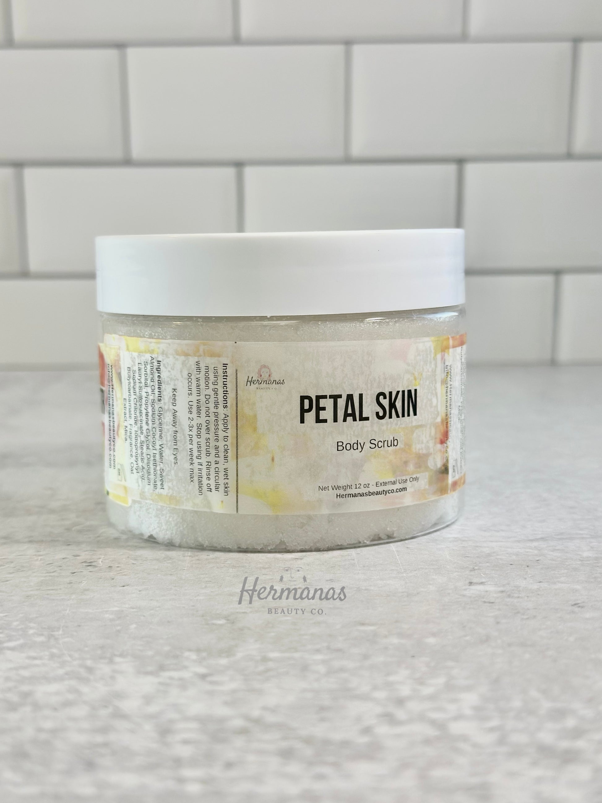 Jar of 'Petal Skin' body scrub on a tiled bathroom wall 