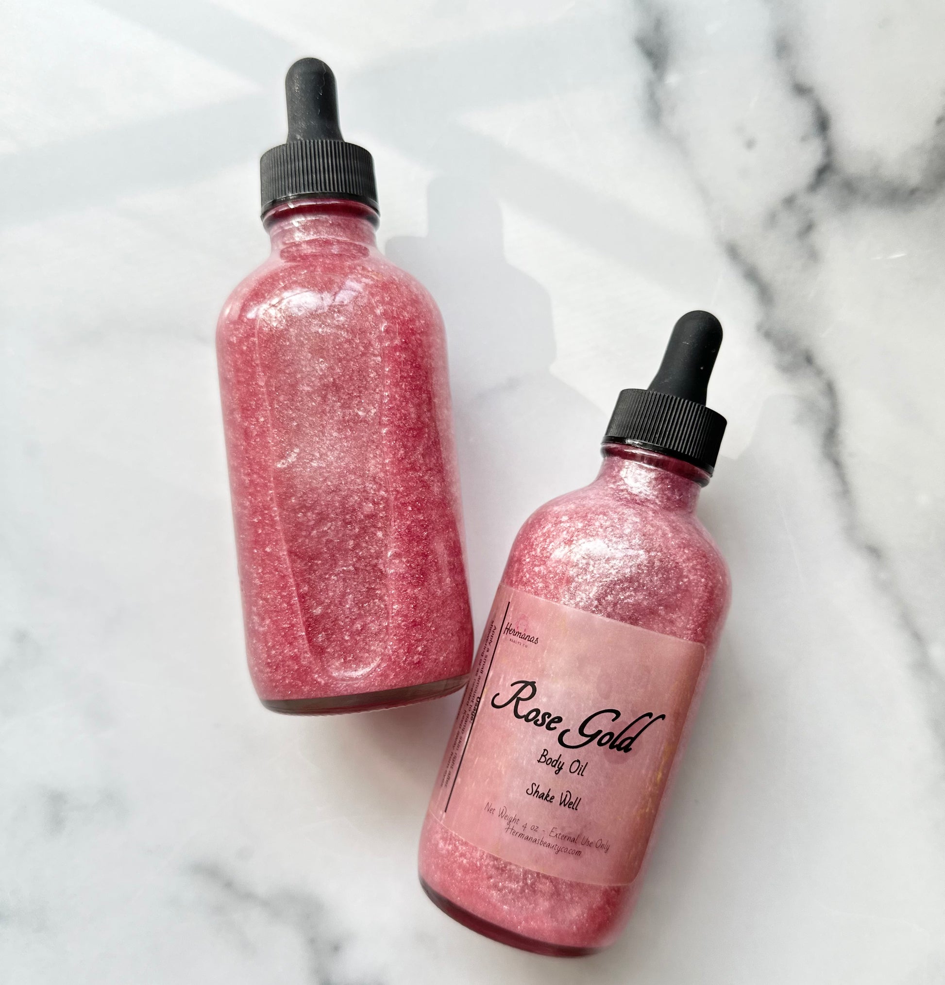 Dark pink shimmery body oil in glass bottle