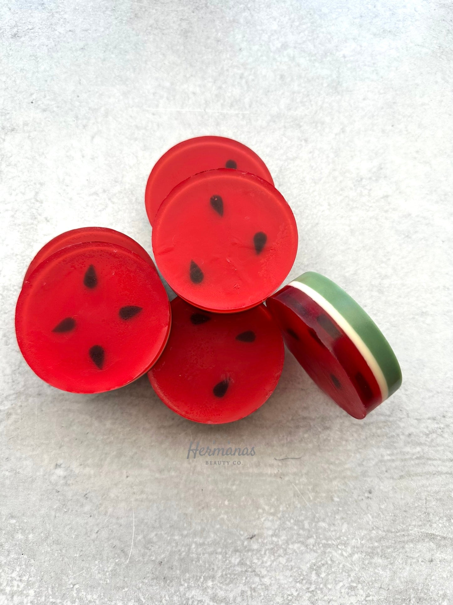 Red watermelon-shaped buttons with black seeds on a textured white background