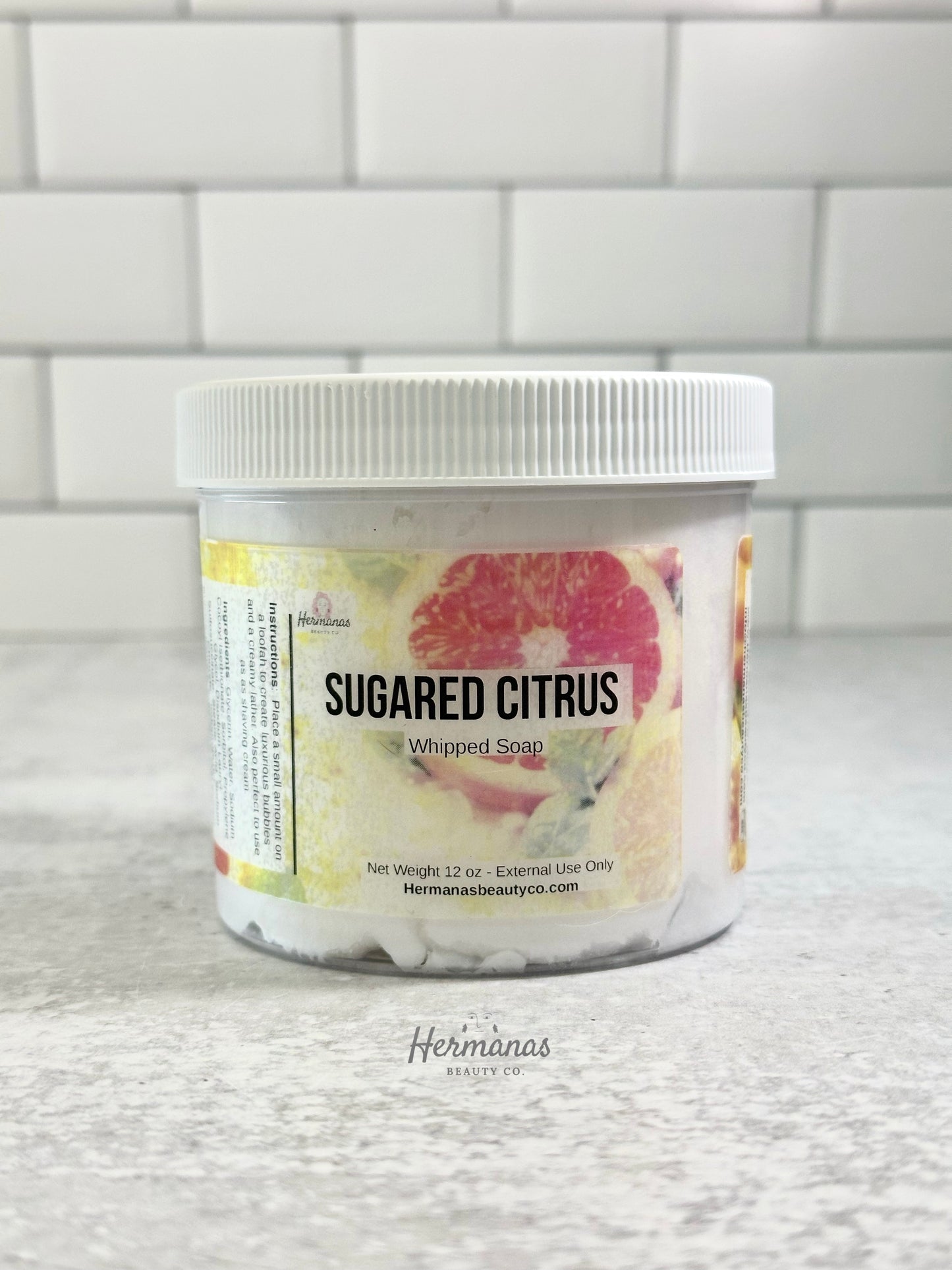 Jar of 'Sugared Citrus' whipped soap with a white lid on a tiled background