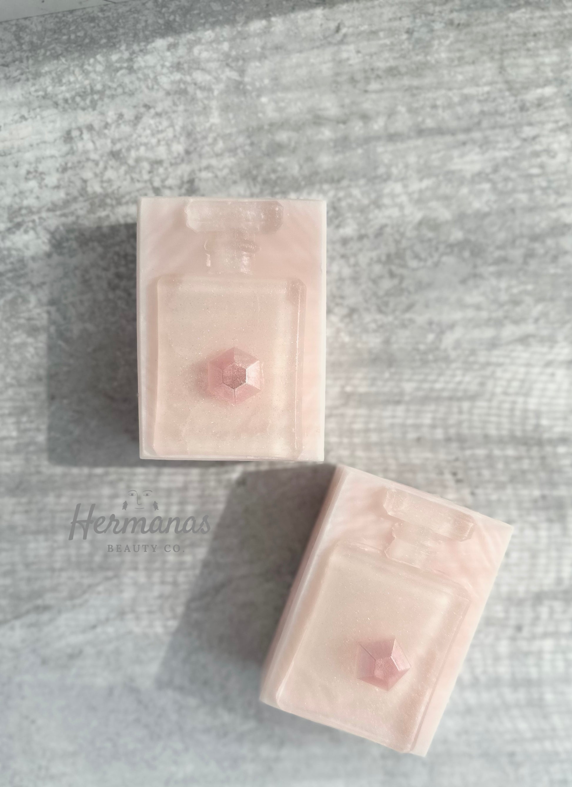 Rectangular shaped light pink soap with a clear perfume shaped soap on top. 