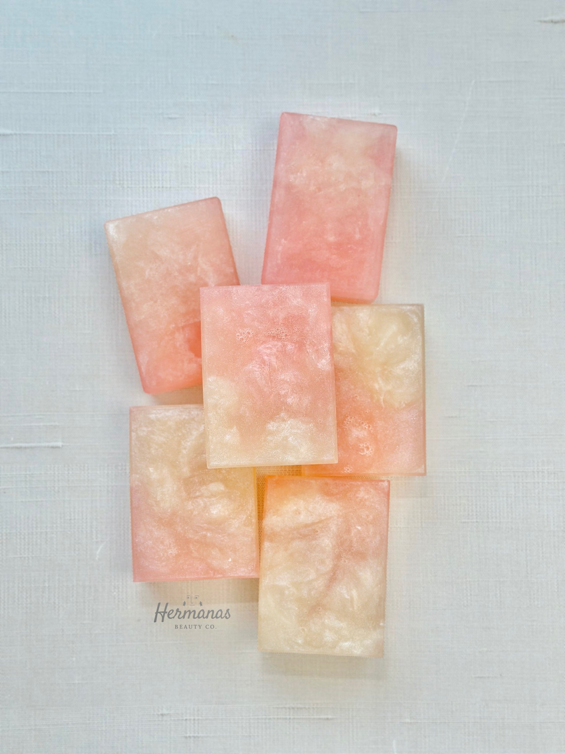 Stack of pink and beige soap bars on a textured white background
