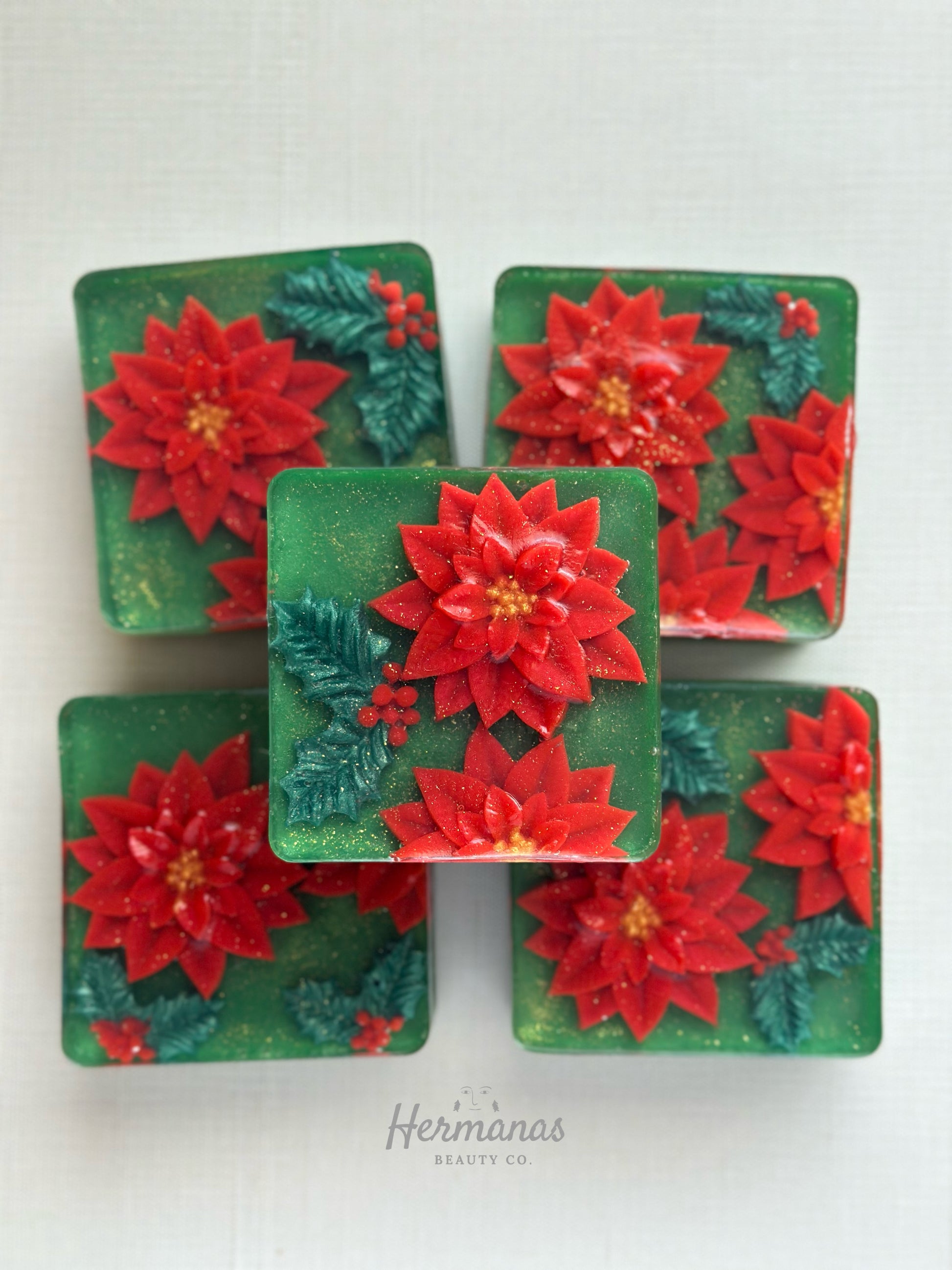 Christmas themed green square soap bar with red poinsettias and holly leaves on top. 