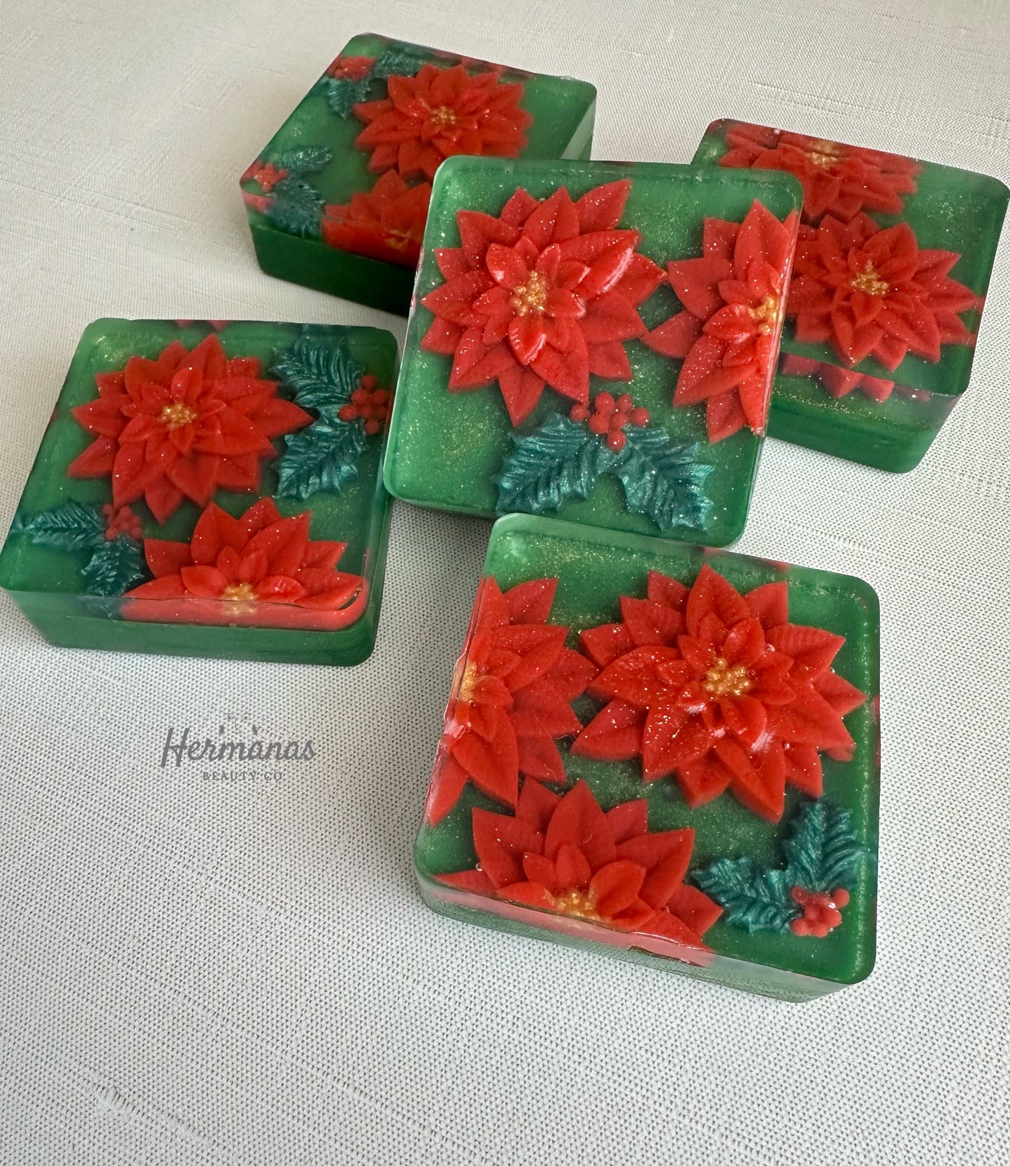Christmas themed green square soap bar with red poinsettias and holly leaves on top. 